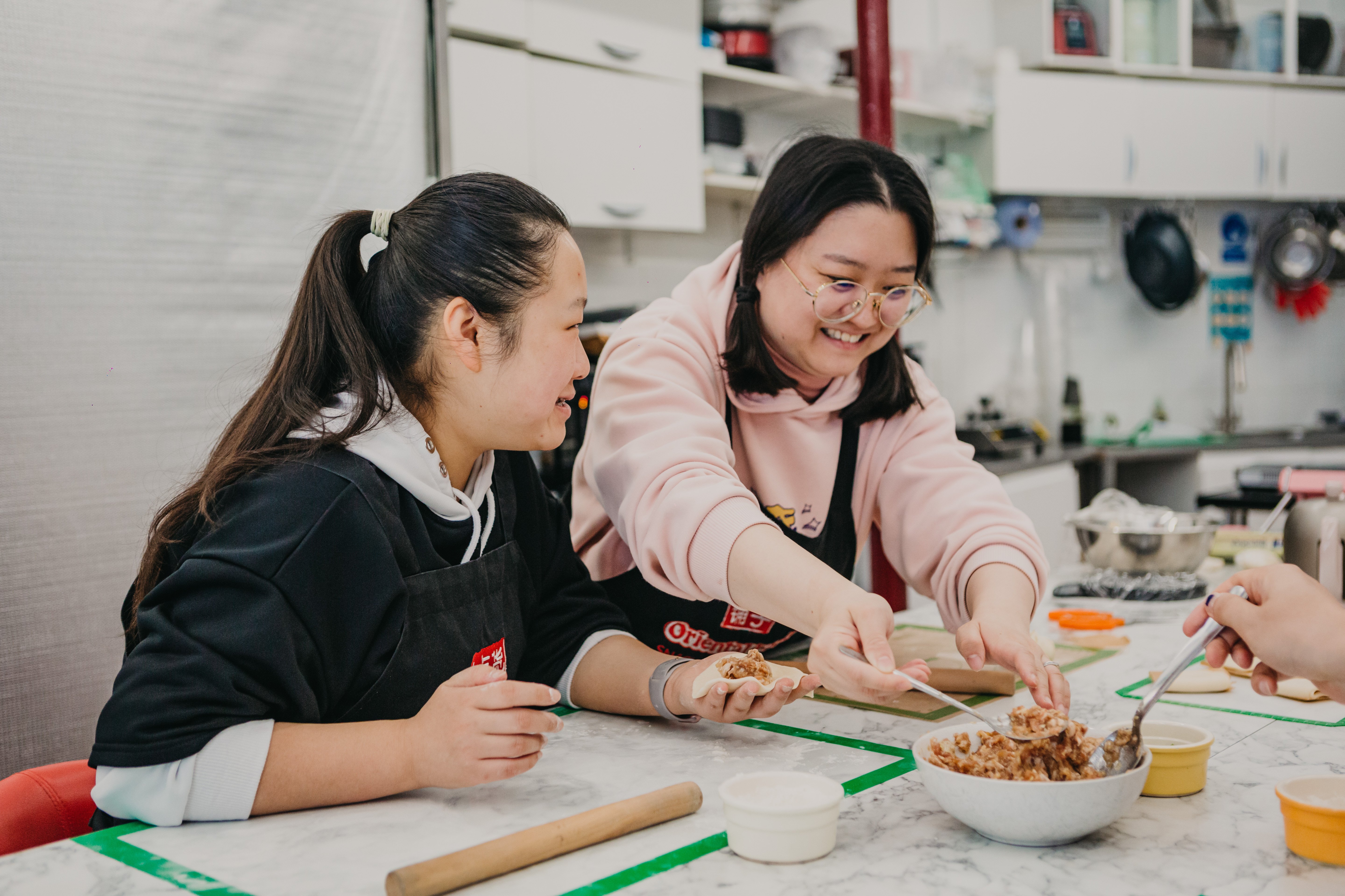 A pair of women are smiling and laughing at a cooking class
